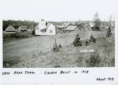View of New Avon, ID. Buildings and church in the foreground
