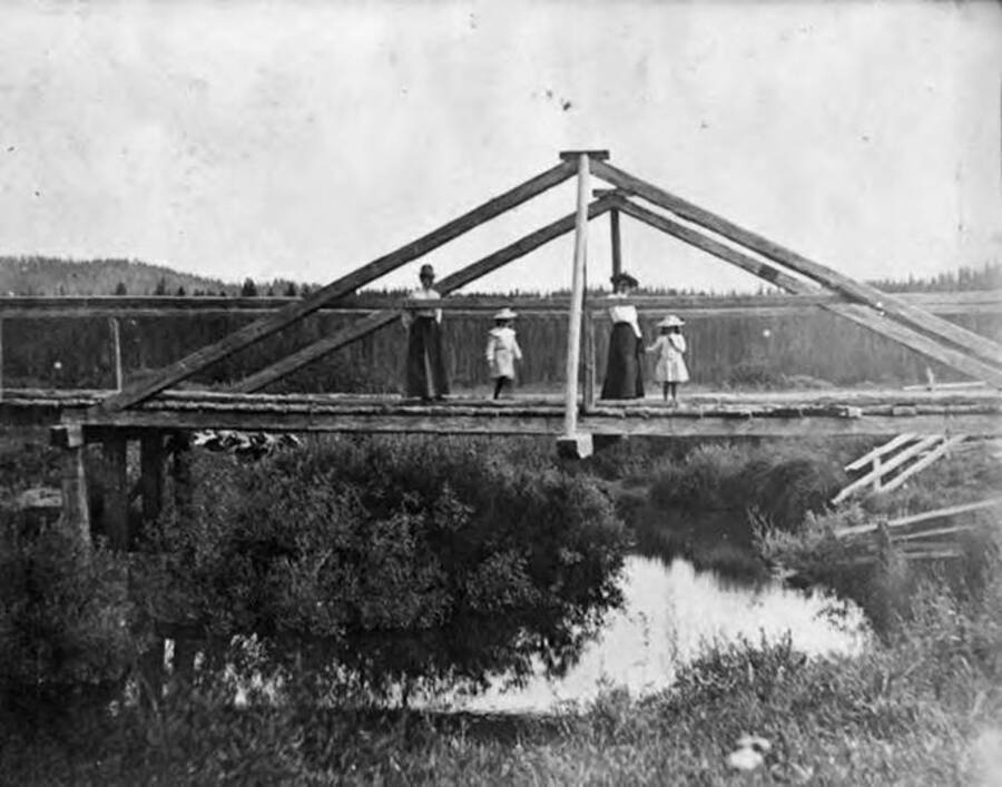 Two women with two little girls stand on the bridge on Pioneer road at Potlatch Creek.
