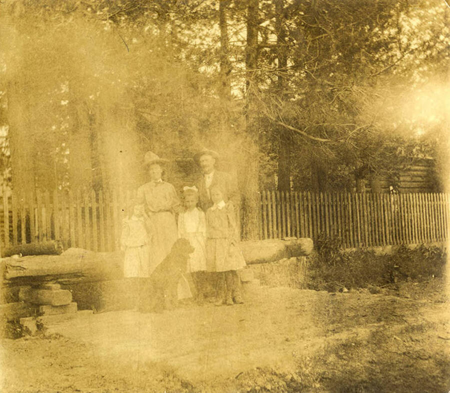 Bovill family pose for a family portrait with their dog in front of a cabin. Pictured: Charlotte and Hugh Bovill, Gwen and Dorothy