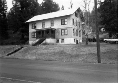 Bovill's hospital with trees surrounding it and cars parked off to the side.