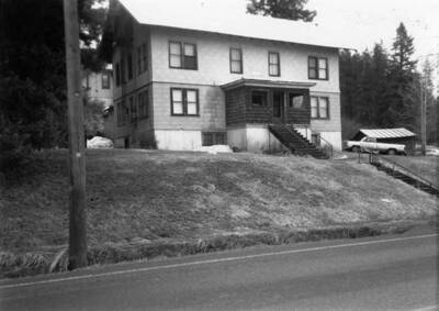 Bovill's hospital with trees surrounding it and cars parked off to the side.