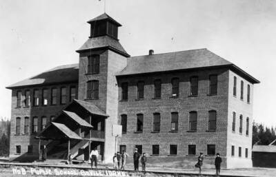 Students stand outside the Bovill Public School with a teacher standing on the stairs.