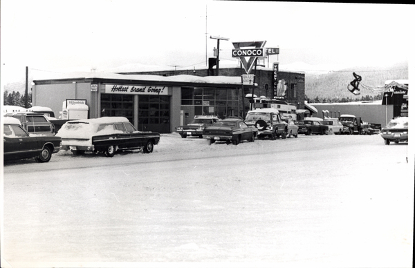 Conoco station, Yacht club, a snow covered road and cars parked on the side. Image contains the text: "Hottest Brand Going   B F Goodrich   CONOCO   AWARD STATION   YANCE CLUB   RICHFIELD"