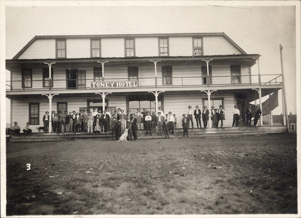 Toney Hotel, when Carl Brown moved to McCall in 1910, the photo has a front facing view of the hotel and several standing in front of the building. Image contains the text: "TONEY HOTEL"