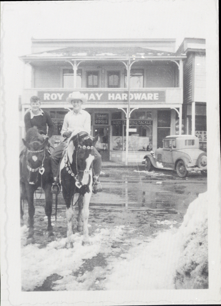 Two men on horseback in from of the Roy May Hardware store during the winter. Image contains the text: "ROY ANNAY HARDWARE"