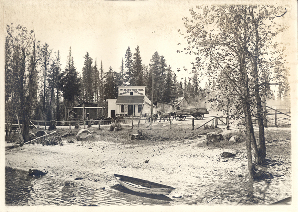 Front view photo of W.B. Boydstun General Store, in frame there is also several wagons pulled by horses, and small canoe. Image contains the text: "WB BOYDSTUN GENERAL STORE CLEARWATER STATION"