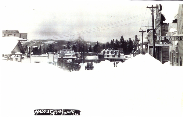 Main St, McCall in winter, lots of snow piled to the sides, some buildings that are in view are Shell, Theatre, Light and Power Service, Goodman’s Cafe, Westcott Oil CO, and more. Image contains the text: "MAIN ST MCCALL IDAHO 1936  GOODMAN'S SUPER SERVICE WESTCOTT OIL CO.  CAFE  CASCADE HOTEL  THEATRE  MCCALL LIGHT & POWER ELECTRIC SERVICE"