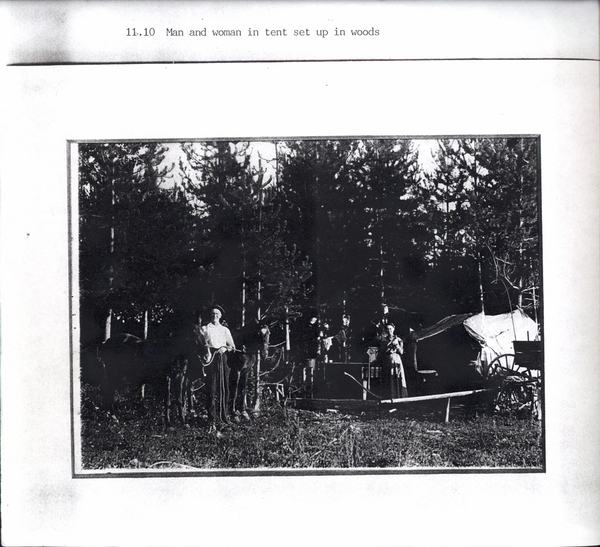 Photocopy of a man and women in tent set up in the woods with a wagon and horses. Image contains the text: "11.10 Man and woman in tent set up in woods"