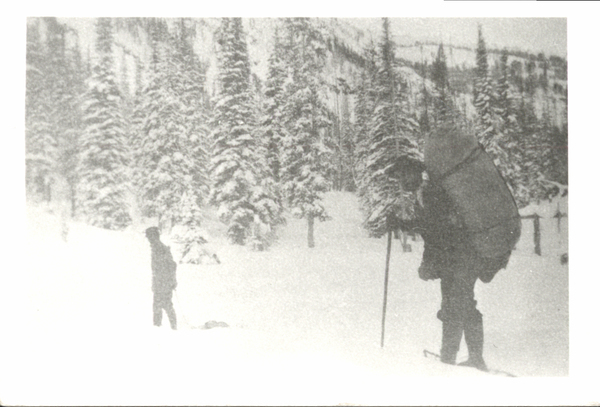 Man backpacking on snowshoes and another man pulling a sled