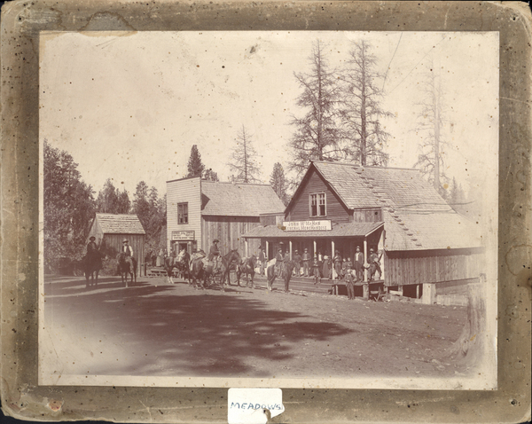 Old Meadows- John McMaHan General Store; crowd of people, some on horseback. Image contains the text: "JOHN McMAHAN GENERAL MERCHANDISE MEADOWS"