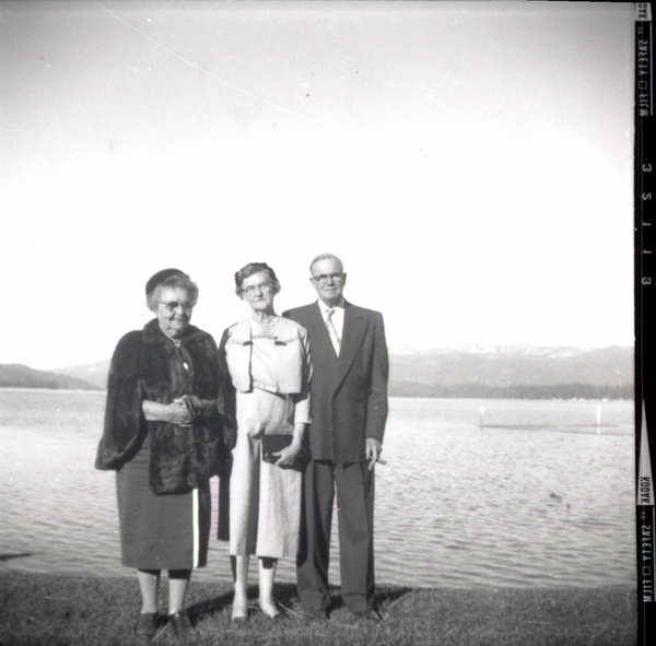 Photograph of three people by the lake, one man, and two women