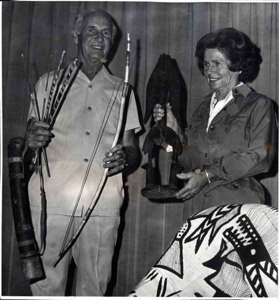 Jayne and Warren Brown with bow, arrows, and an African statue and cloth