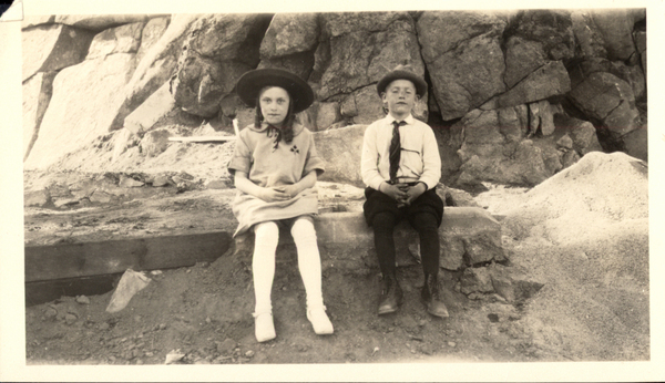 Little girl and boy seated outside