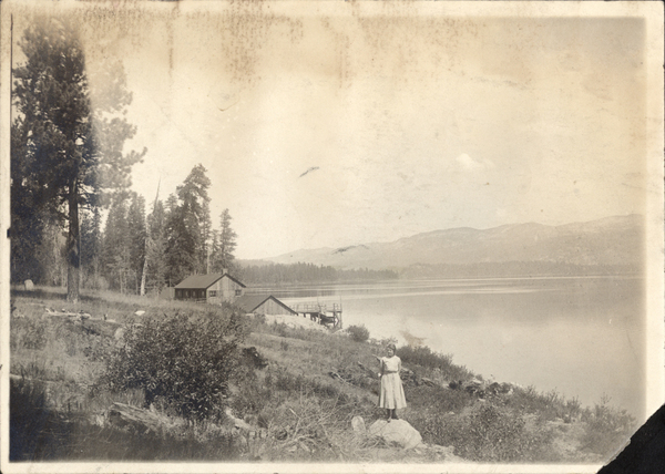 View of a lake, cabin, dock, and a women in the foreground