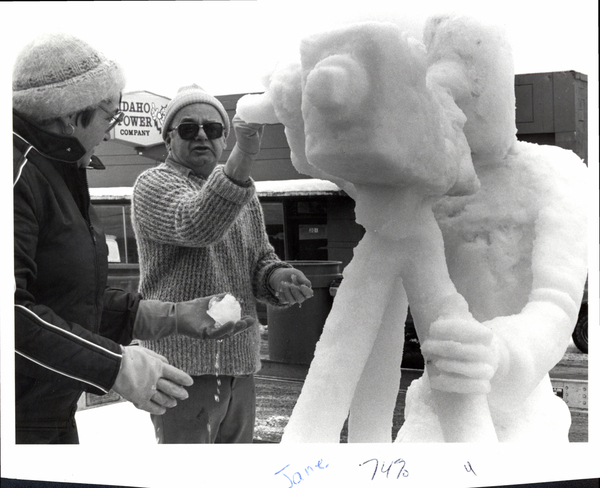 View of Idaho Power Company, a man and women holding snow/ice next to a ice sculpture of a photographer with a camera