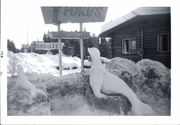 An ice sculpture of two seals. Image contains the text: "FEB 68  FORDS  VACANCY  GAS for LES"