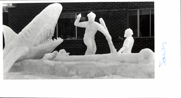 An ice sculpture shark jumping onto a boat rowed by two people