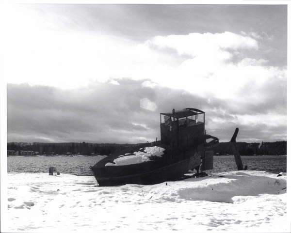 Boat banked on the snow and the lake in the background