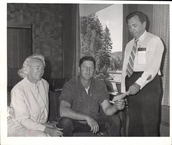 Three people, one man handing a check to another man