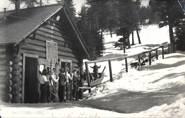 Original Postcard TB-15 Payette Lakes, Idaho, Little Ski Hill, the photo shows skiers waiting to ride a sled up the hill, on the back it states, “I rode these sleds to go skiing when in was a child. Property of Jeannie Eddins, Donor.”