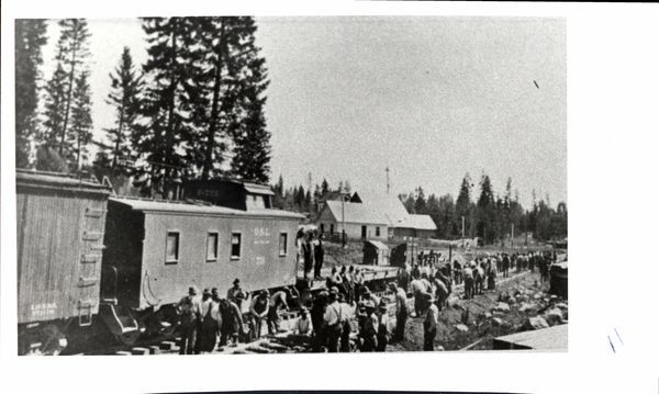 A train caboose of O.S.L with crew laying parallel track