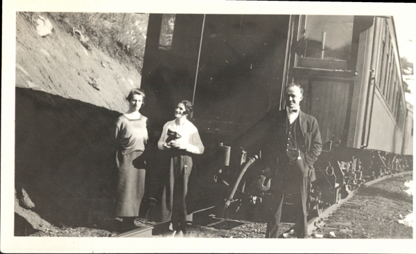 A man and two women posing by the train