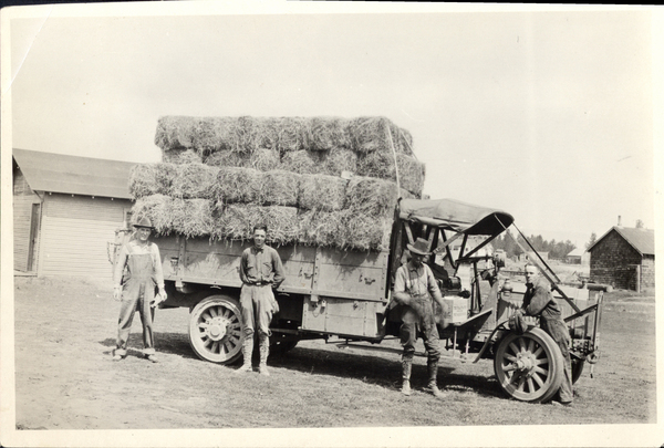 Truck loaded with hay bales and four men