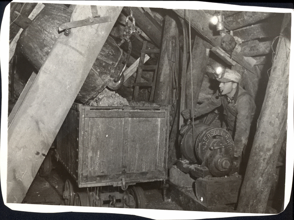 Tram car in a mine with a man smoking a pipe. Image contains the text: "INGERSOLL RAND"