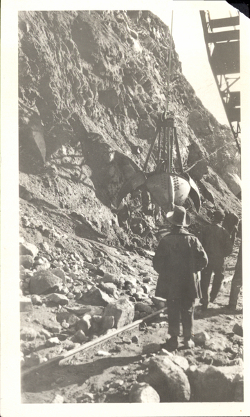 Power shovel on hillside and men watching