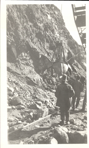 Power shovel on hillside and men watching