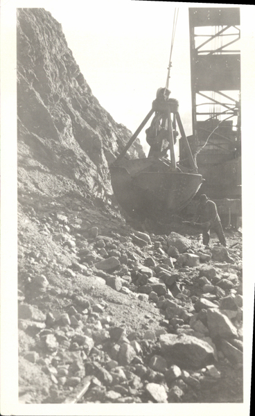 Power shovel on hillside and man working with a shovel