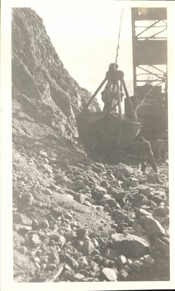 Power shovel on hillside and man working with a shovel