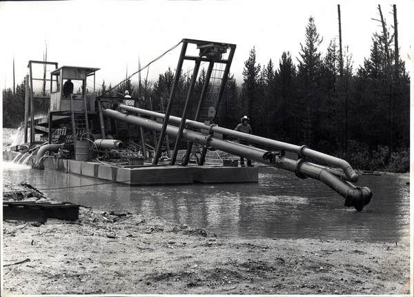 Dredging in the river, three men are also in view