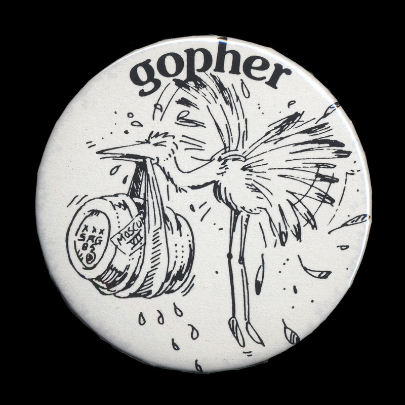 A white, circular button with an image of a crane straining to carry a barrel reading "MosCon VII" in a cloth. "Gophers," a term used to describe MosCon volunteers, is written above the illustration.