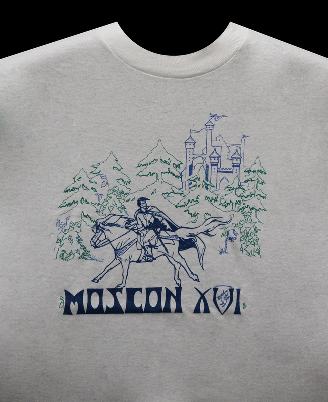 The official MosCon XVI shirt, depicting a man in a cape riding a horse in front of a castle. The shirt was manufactured by Chameleon Products in Moscow, ID, and was screenprinted using thermochromatic ink that changed color based on temperature.