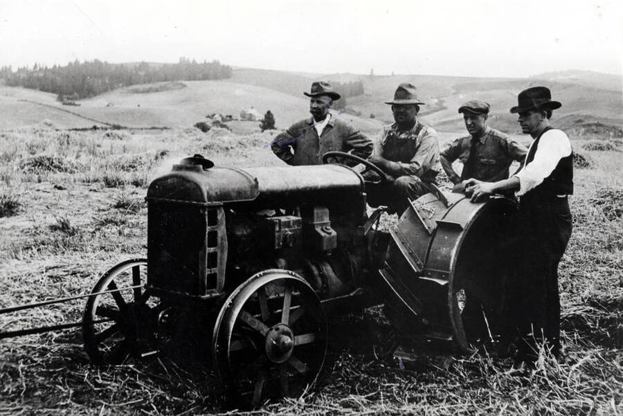 Threshing peas on Arnold Lyons farm using a Fordson tractor to power the thresher. Lyons at left, George O'Connor on tractor, unknown man next and Tim Sullivan, Ford dealer of Moscow.