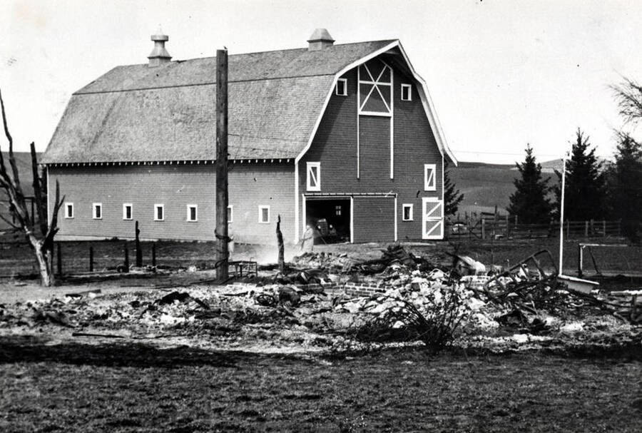 This is the F.W. (Fred) Hagedorn barn on Airport Road between Pullman and Moscow.  It was constructed along with 3 other farm buildings in 1920.   The smoldering remains of the farmhouse are in the foreground; the farmhouse burned following a chimney fire in 1940.  Shingles from the burning house lit the barn roof on fire (a small black area is visible by the left cupola), and a neighbor from the Hawley farm climbed into the rafters, sheared off the right cupola to gain roof  access, and extinguished the fire using a bucket and rope.   The barn is  still in great condition and is listed on the Washington State Historic Barn Register.