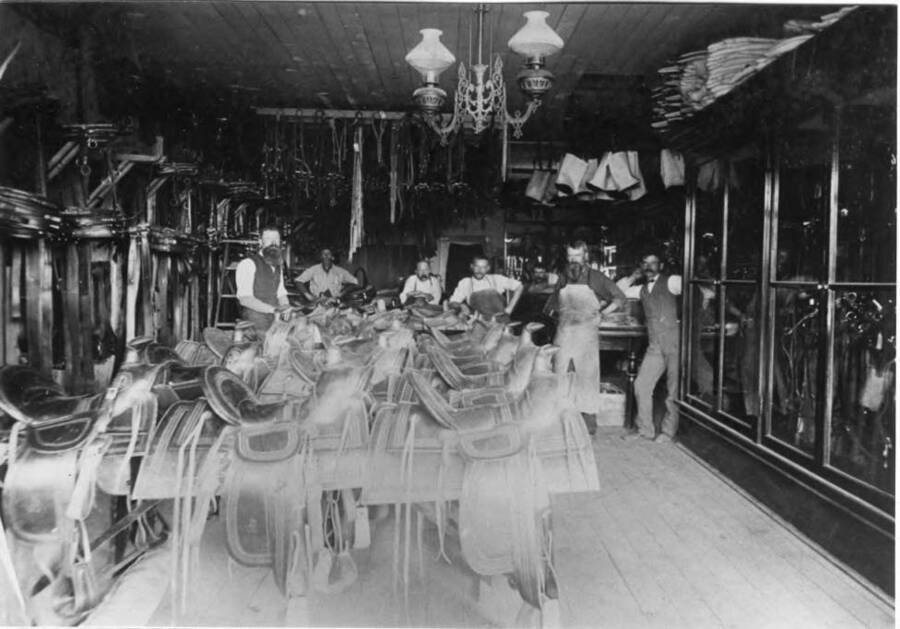 Inside the George Weber Harness Shop. George Weber at right with mustache and wearing vest. Henry Ririe with full beard and wearing apron next to Weber was Carol Ririe's uncle (Willie in Snow in the River). Jacob Hoke at left with full beard and wearing vest. Hoke and family owned and operated the Latah Hotel at 719 South Main and the residence north.