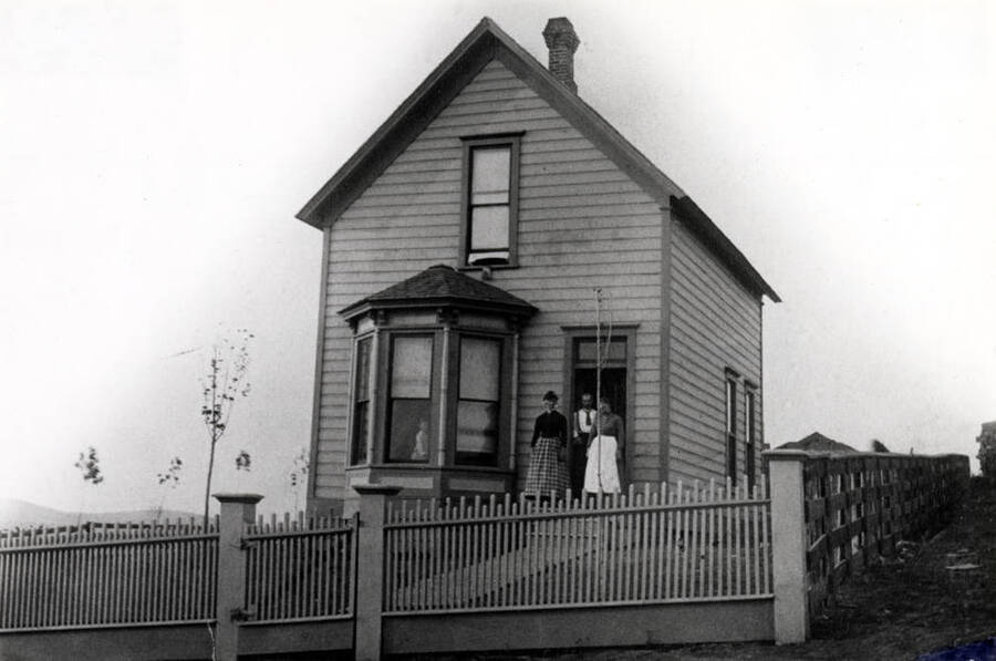 Frank J. Yangel residence, 216 East A Street. Believed to have been built in the early 1880s. Picture taken 1888. Yangel in doorway and wife Anna at right. Girl and woman in dark dress, neighbors. Yangel was an early tailor and had his shop at 107 South Main Street for many years.