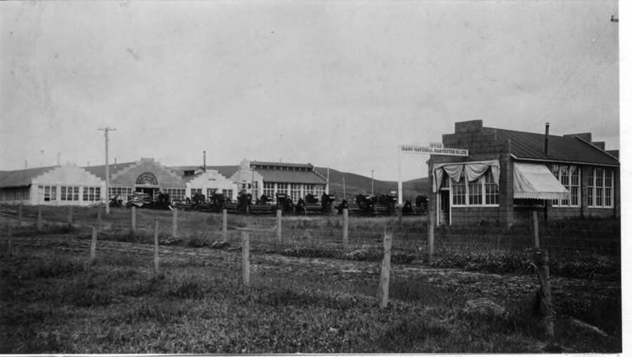 Idaho National Harvester Company buildings built in 1911 west of Main Street between D  and E streets near the Spokane & Inland Electric railroad tracks. D Street in foreground and office at right. Now site of Rosauer's, Drug Fair, and Yellow Front. From Main Street west to paved parking area as of 1977.