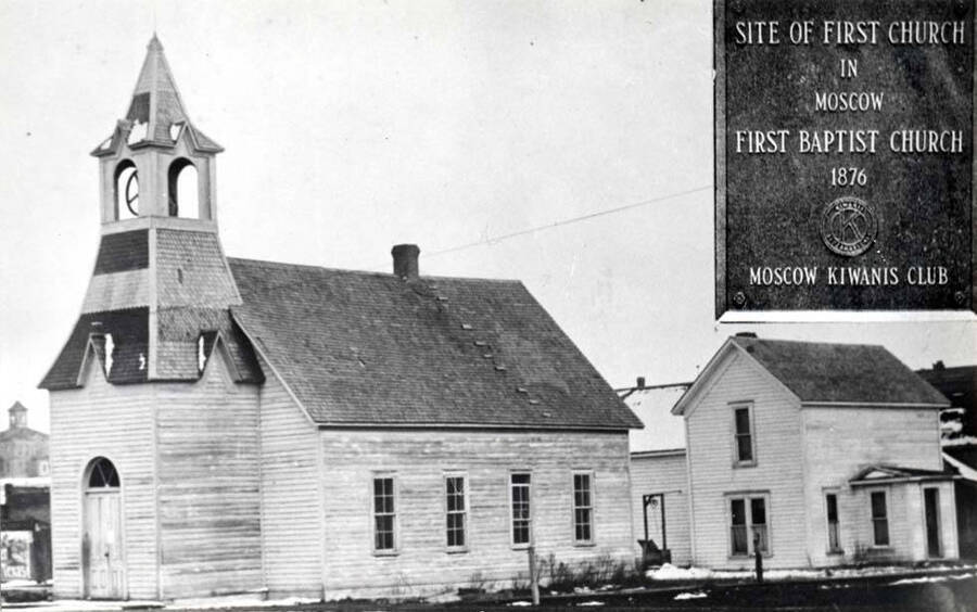 First Baptist Church built in 1876 and organized August 5, 1876. Located at the southeast corner of First and Jackson streets. First church in Moscow. Sometime after the church was built the entrance and bell tower were added on the north end. Baptist parsonage is the house at the right of the church.