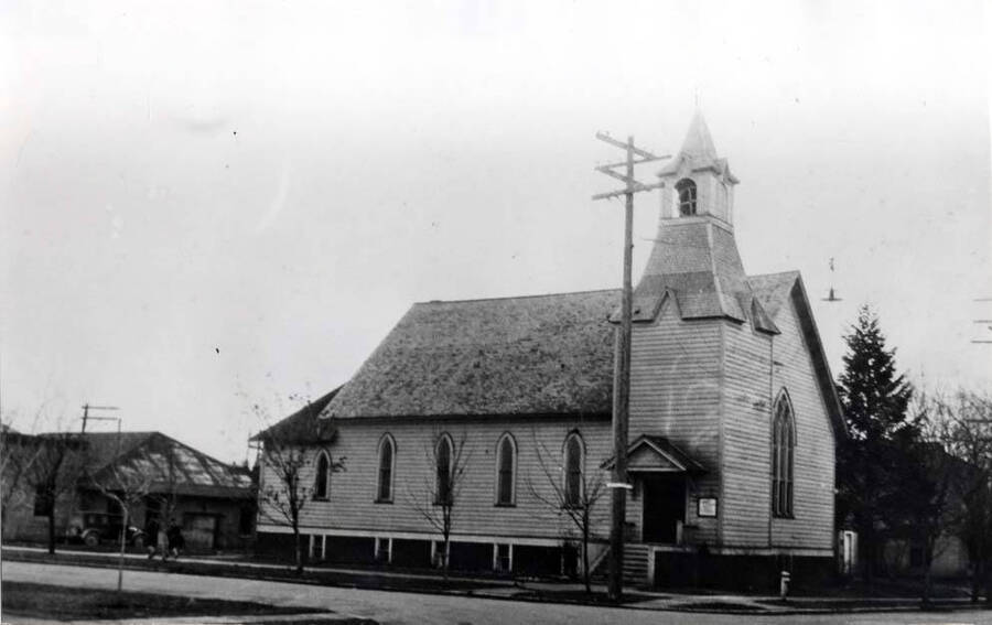 First Baptist Church in May 1932 after it had been moved onto a concrete foundation with a full basement. Extension had been added on the east end and the entrance and bell tower moved to the side from the end of the church. Parsonage is seen at the right of the church beyond the trees.
