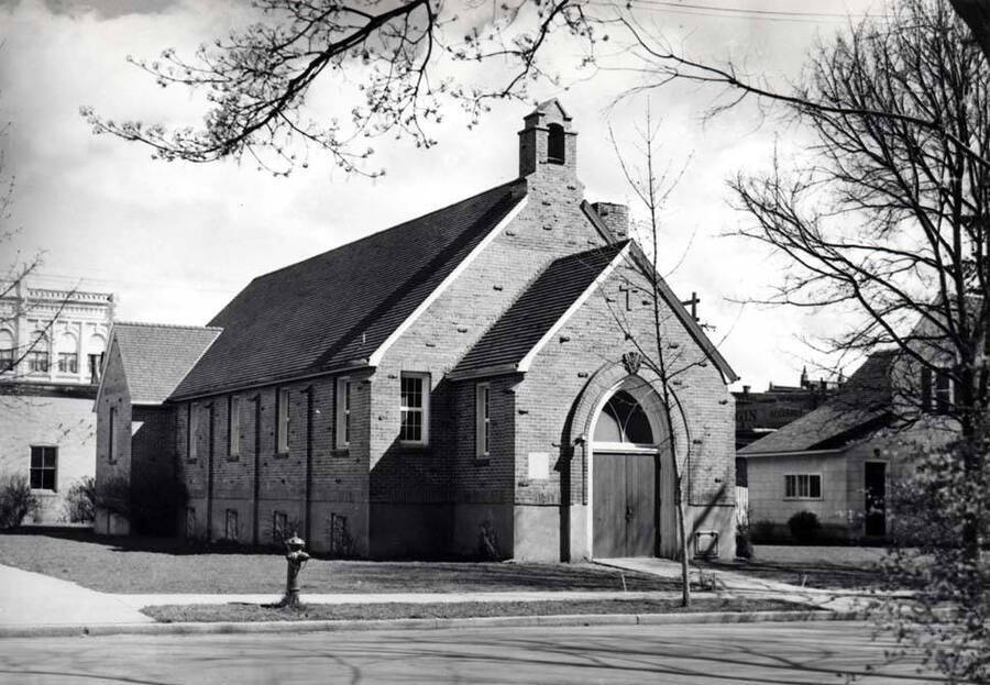 New First Baptist Church was built in 1938 and dedicated April 16, 1939, at the location of the old church at the southeast corner of First and Jackson streets. Parsonage is at right of the church.