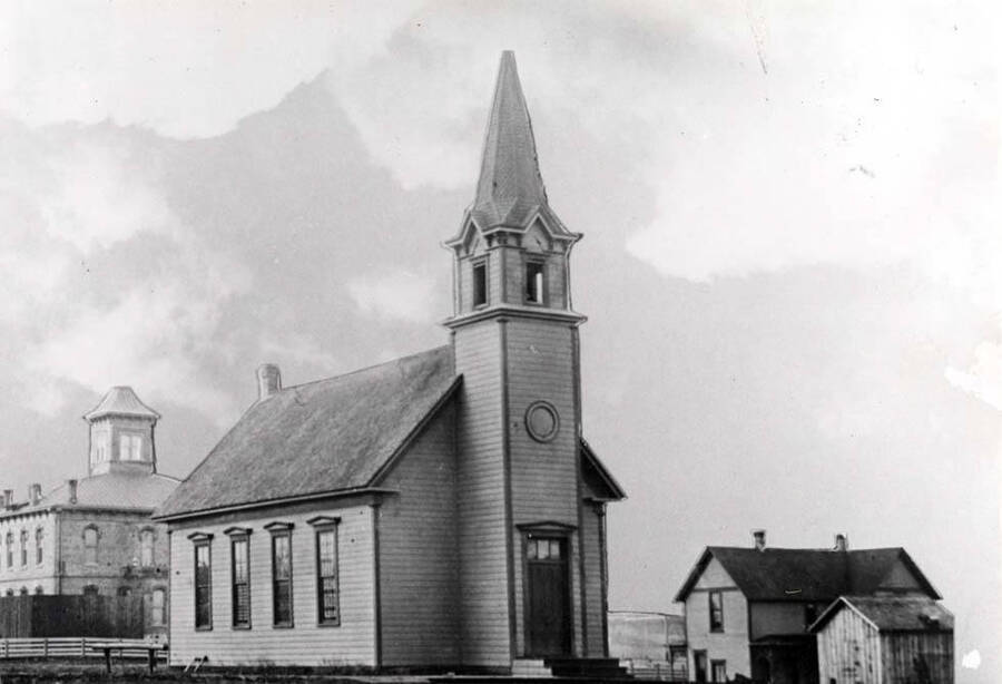 First Presbyterian Church organized in 1880 and built in 1883 at the southwest corner of Fourth and Van Buren streets. Latah County's first courthouse at left built in 1888-89. Picture 1890s.