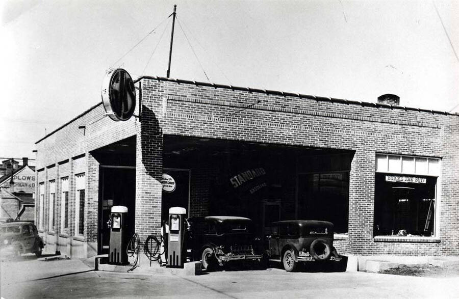 Northwest corner of Sixth and Washington streets. Buick dealership. Butterfield & Elder Implement Company, farm equipment beyond. Jack Lawton. Janet Long Gray and Samuel Long owned service station.