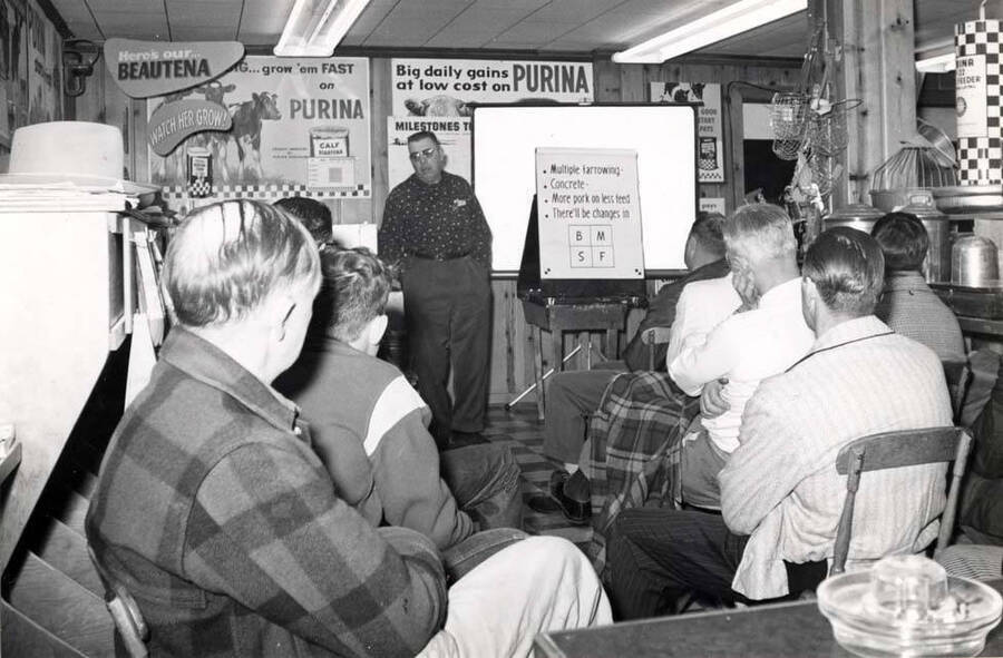 Lyle Smith, the Purina salesman for this area, conducting a hog meeting at the Washburn Farm Store, showing the results of proper feeding.