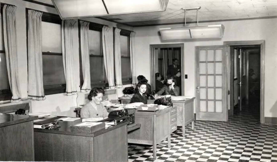 Front office of the Washburn-Wilson Seed Company at the southeast corner of A and Almon streets. Lee Walker Mathews, front desk; second desk, unknown. Minnie Smith, office manager on phone at third desk. Hodgins Drug Store, Charles Dimond, photographer.