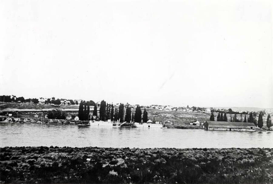 Looking east across Snake River showing two boats at the dock and the warehouse at the right. High water when picture taken.