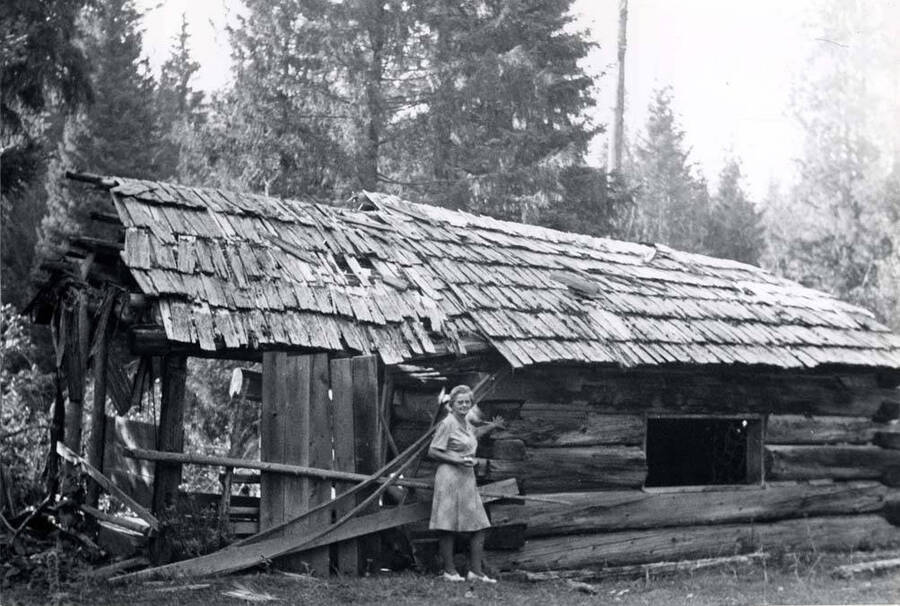 Peggy [Mrs. Clifford M. Ott] and a miner's log cabin located in the Hoodoos. Picture by Clifford M. Ott in 1976.