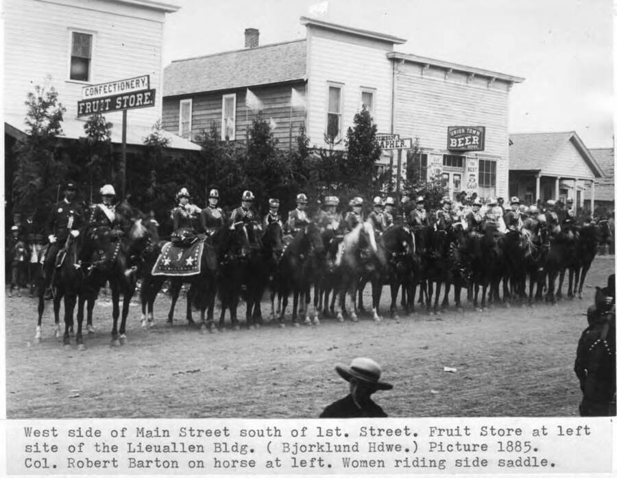 Fruit store at left site of the Lieuallen Building. (Bjorklund Hardware) Picture 1885. Colonel Robert Barton on horse at left. Women riding side saddle.